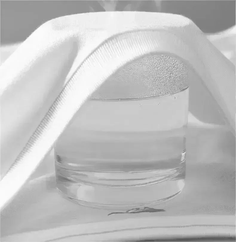 Glass of water with condensation, partially covered by a white cloth, creating a steaming effect.